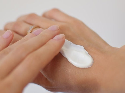 Cream being smoothed into the back of a hand